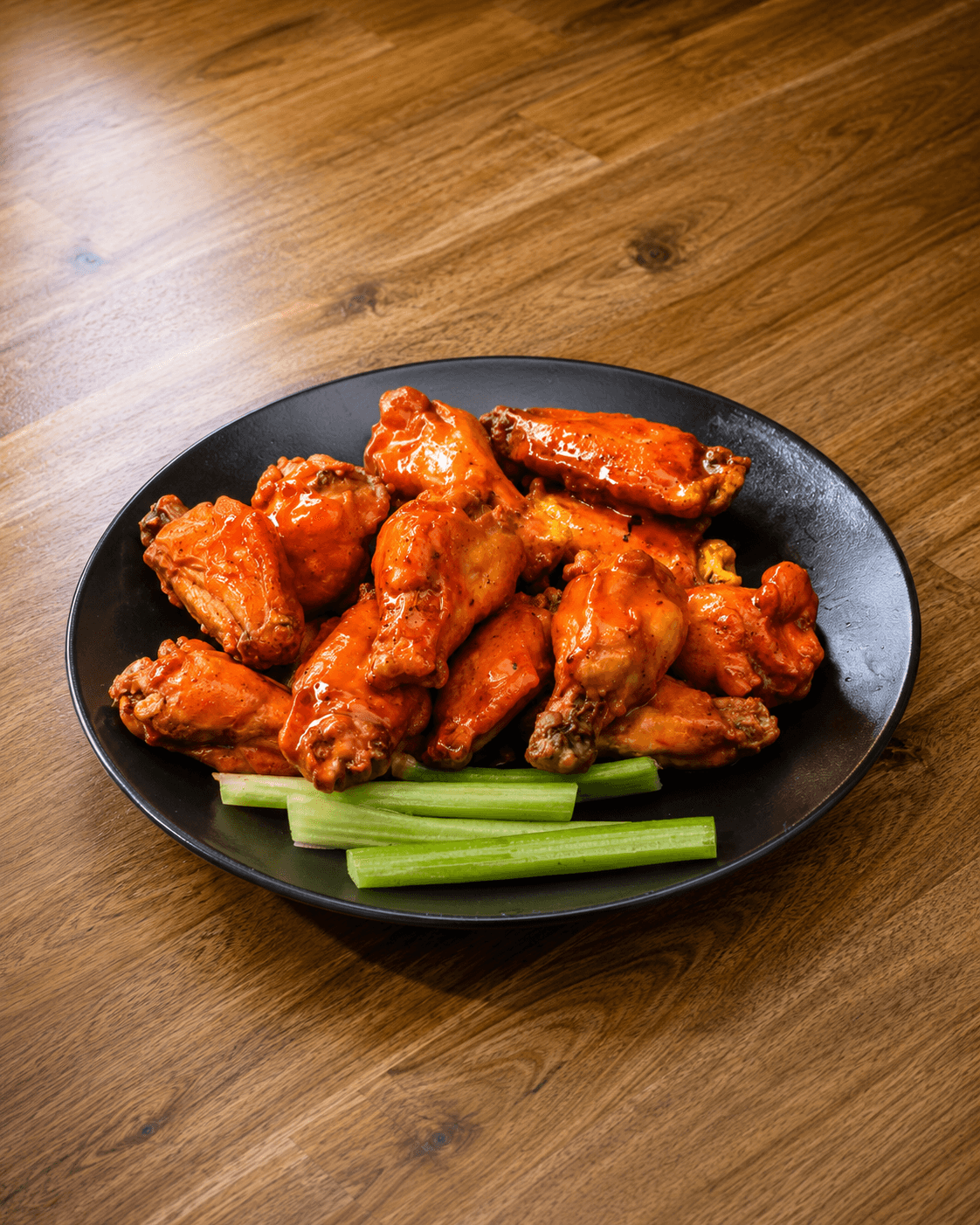Buffalo wings with celery on a black plate