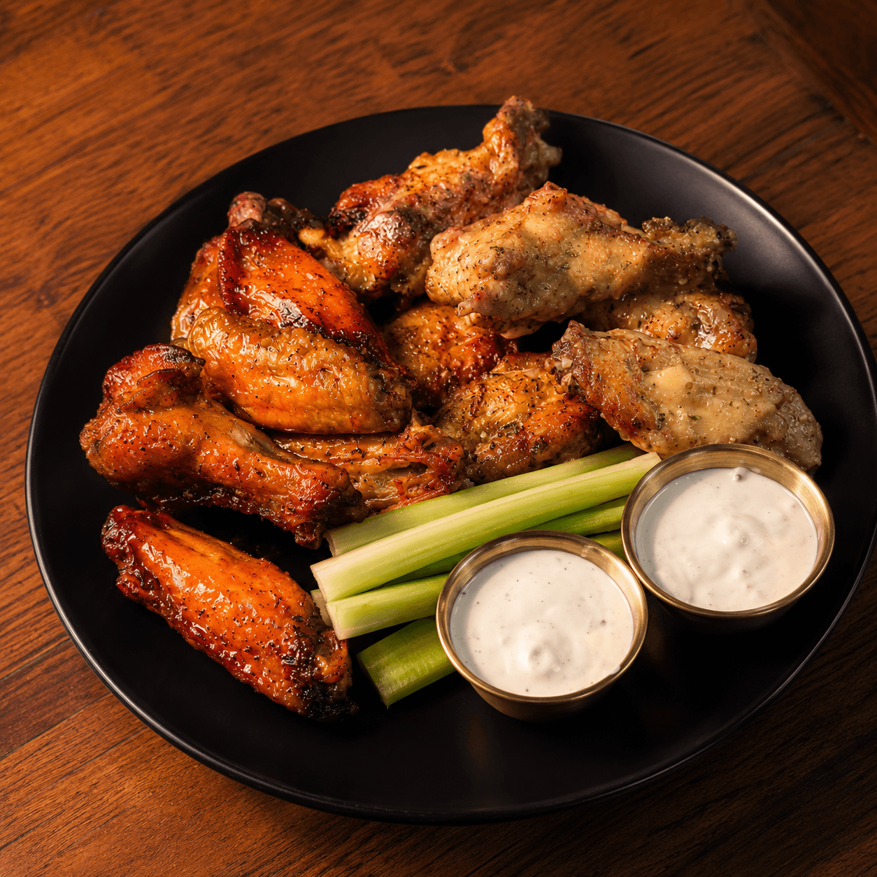 Chicken wings with celery and ranch on a black plate